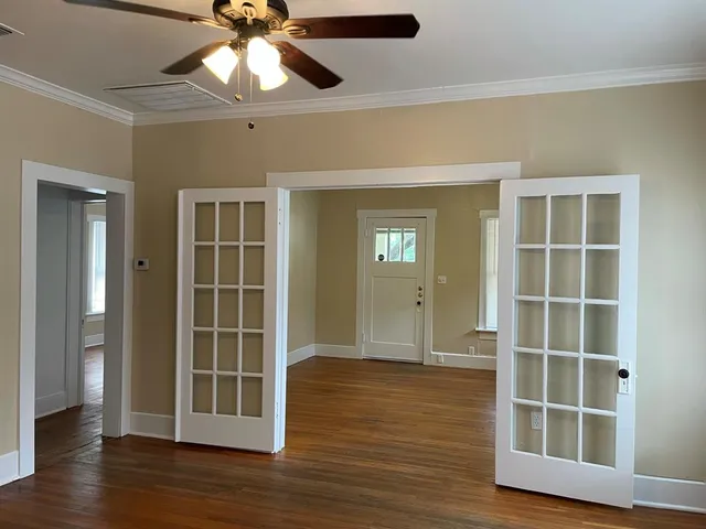 an empty room with wooden floor closet and windows