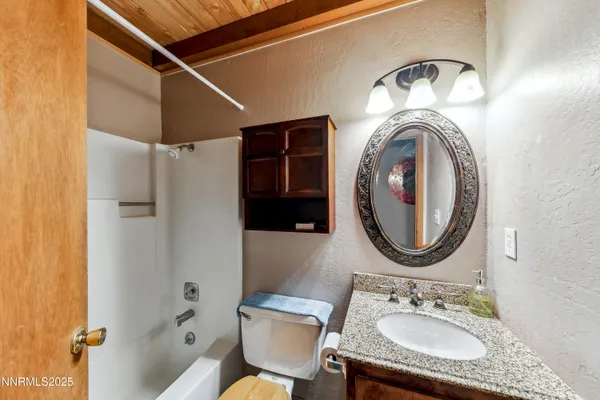 a bathroom with a granite countertop sink mirror vanity and toilet