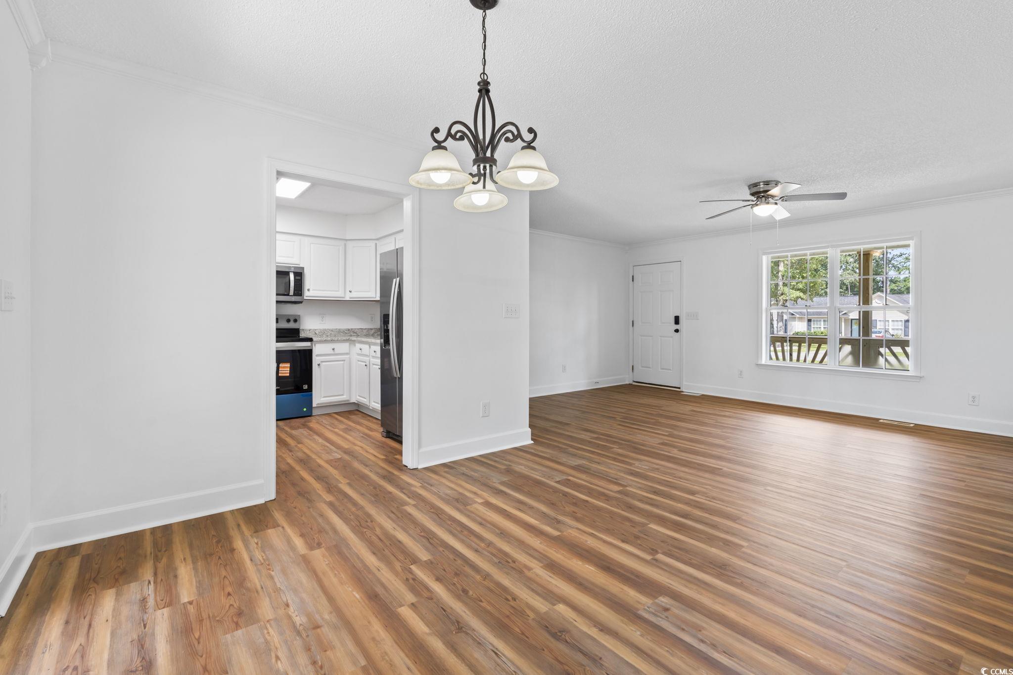 568 Rosedale Drive Aynor, SC 29511 - Photo 10 of 38 Unfurnished living room with dark wood-style flooring, a chandelier, ceiling fan, and crown molding