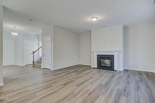 a view of empty room with wooden floor and fireplace