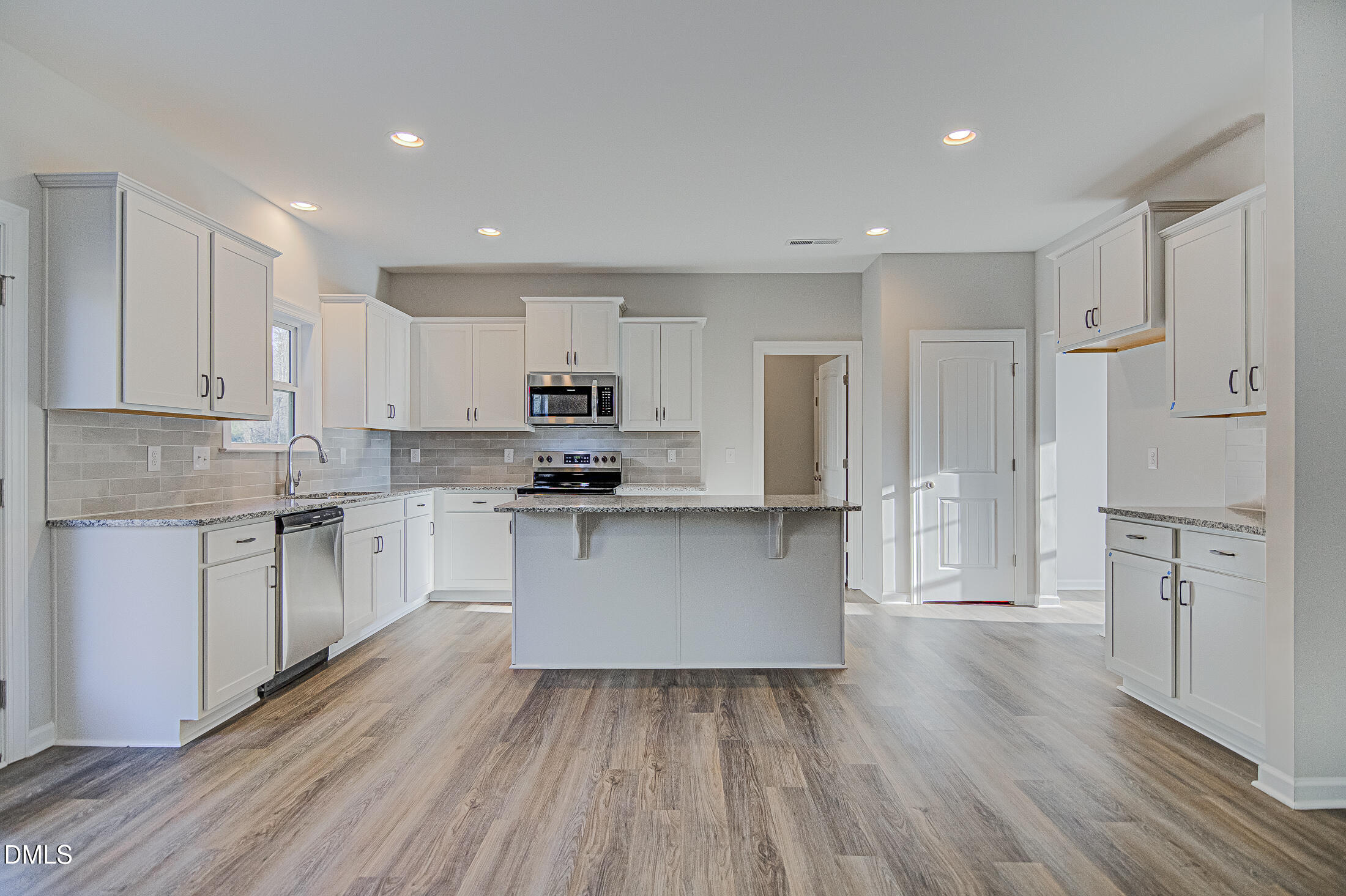108 Starlet Ridge Way Clayton, NC 27520 - Photo 8 of 37 a large white kitchen with a refrigerator a sink dishwasher and white cabinets with wooden floor