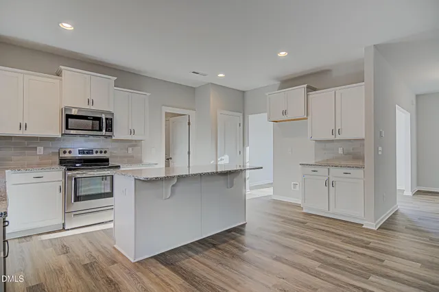 a kitchen with granite countertop white cabinets and stainless steel appliances