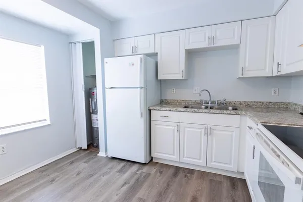 a kitchen with granite countertop white cabinets and white appliances