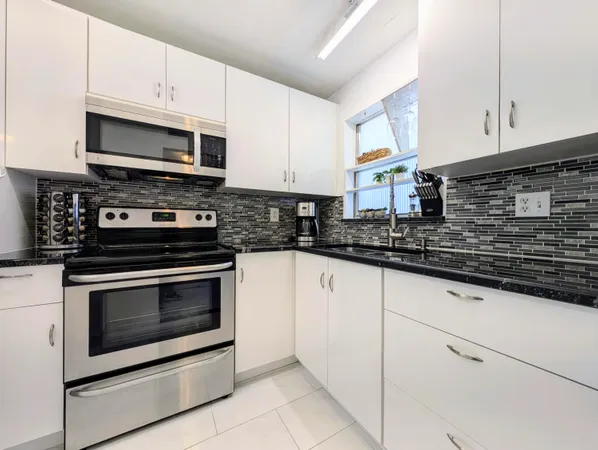 a kitchen with granite countertop white cabinets stainless steel appliances and a sink