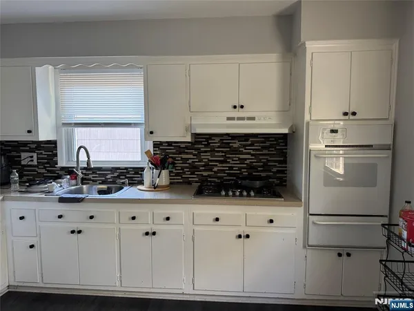 a kitchen with white cabinets and appliances
