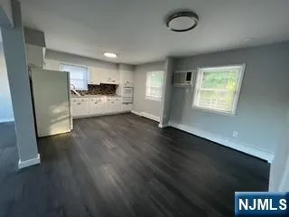 a view of a kitchen with refrigerator and wooden floor