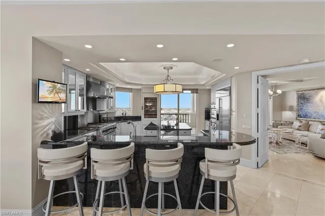 a dining room with stainless steel appliances kitchen island granite countertop a dining table chairs and view living room