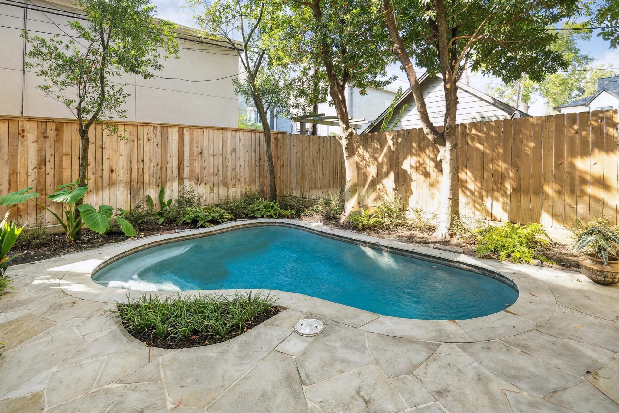 6106 Fordham Street Houston, TX 77005 - Photo 11 of 33 Tranquil backyard with mature trees, stone patio, and a refreshing pool bordered by thoughtful landscaping for added privacy.