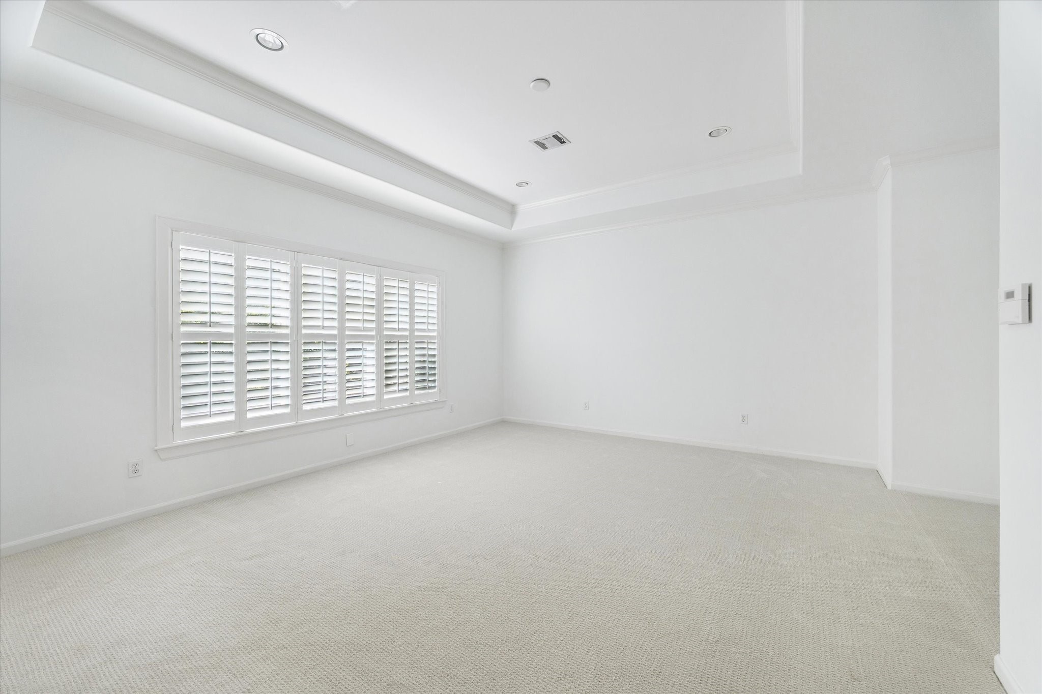 6106 Fordham Street Houston, TX 77005 - Photo 15 of 33 The serene primary suite features plush carpet, tray ceiling, and plantation shutters that softly filter natural light—creating a peaceful retreat with plenty of room for a sitting area.