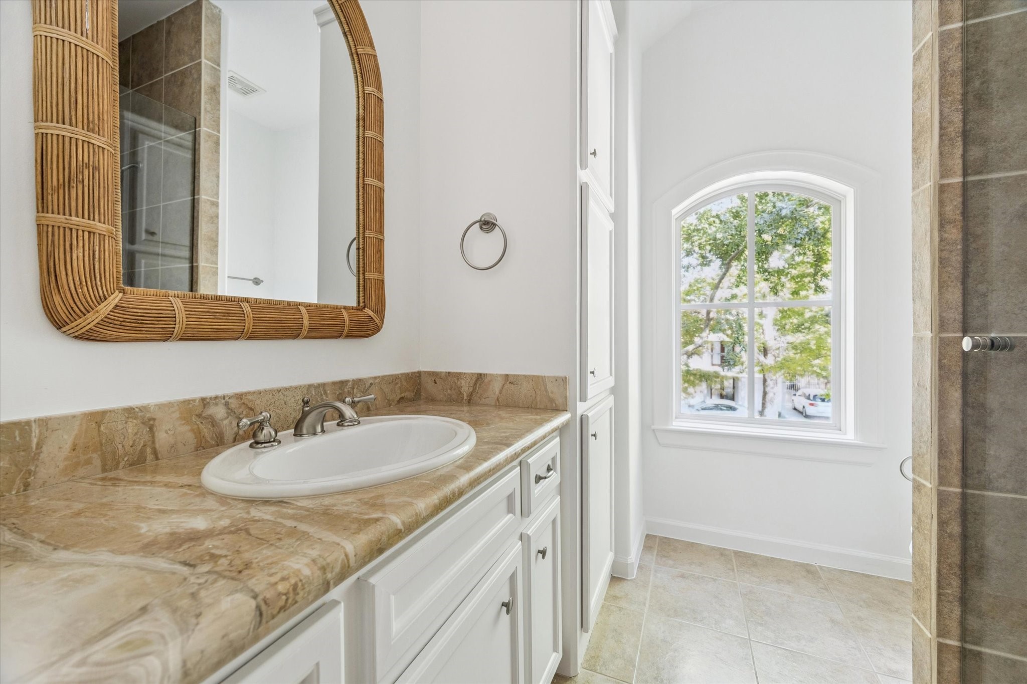 6106 Fordham Street Houston, TX 77005 - Photo 23 of 33 Beautifully appointed bath with a marble countertop, built-in cabinetry, and an arched window that fills the room with soft natural light.