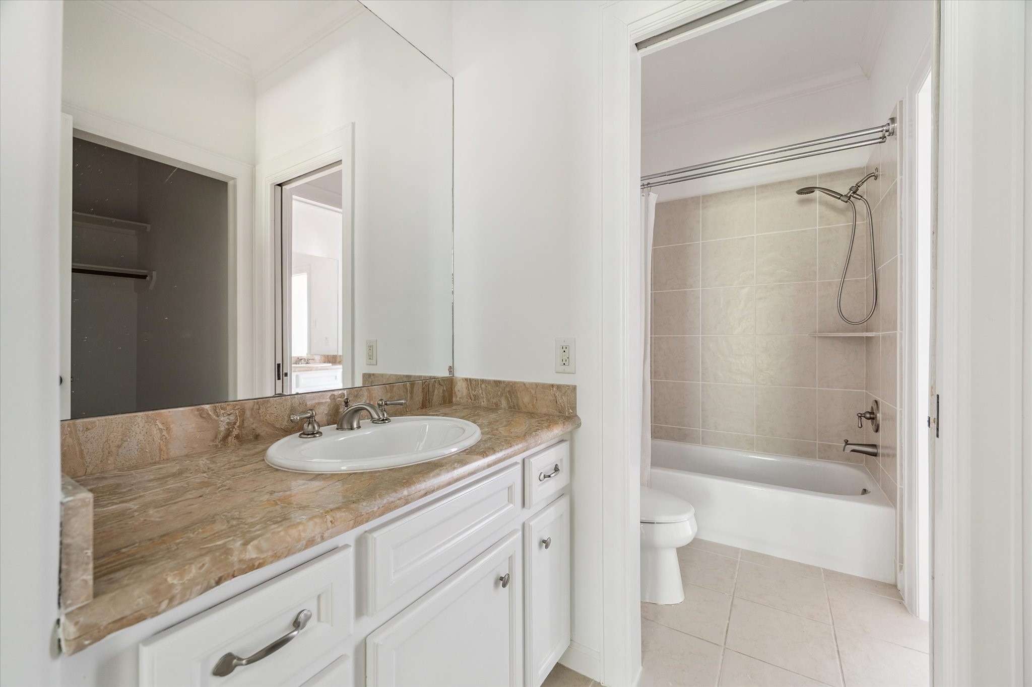 6106 Fordham Street Houston, TX 77005 - Photo 26 of 33 Shared secondary bath with a tub and shower combination, neutral tile surround, and coordinating marble countertop vanity.