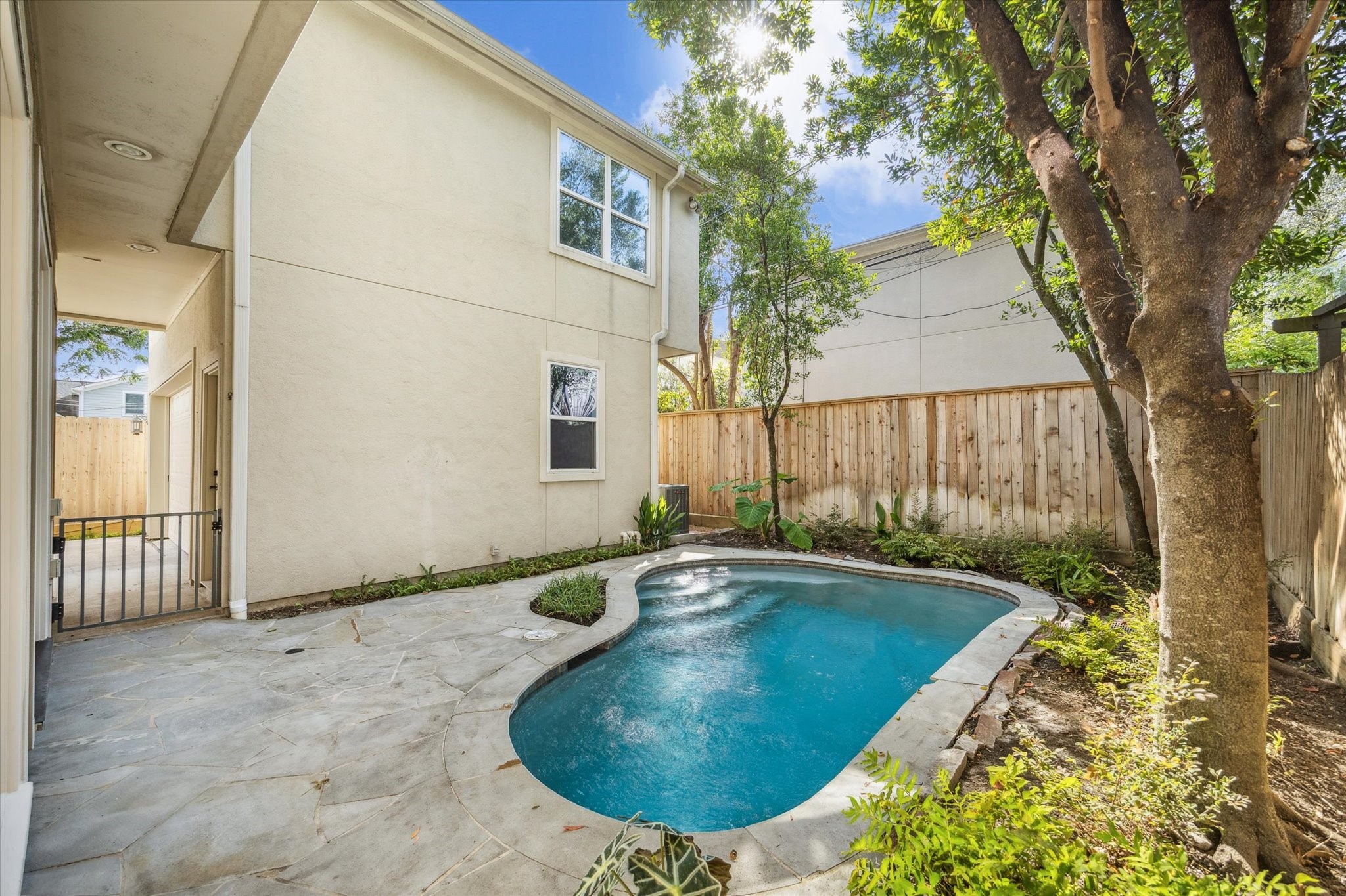 6106 Fordham Street Houston, TX 77005 - Photo 30 of 33 A private backyard retreat featuring a flagstone patio and sparkling pool surrounded by lush greenery and shade trees—perfect for relaxing outdoors or entertaining guests.