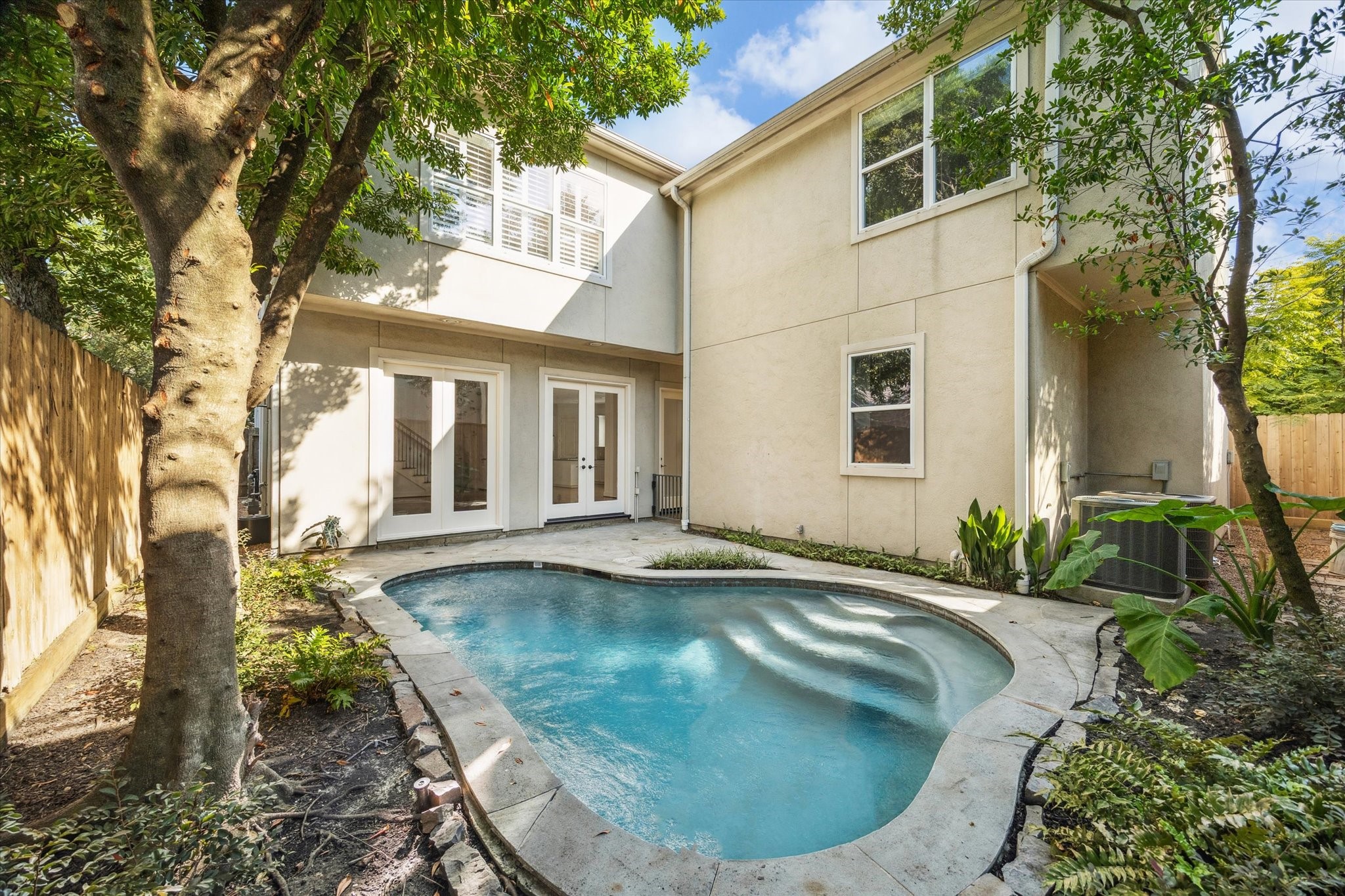 6106 Fordham Street Houston, TX 77005 - Photo 31 of 33 View of the pool from the back of the home, highlighting French doors that open from the living area to create seamless indoor-outdoor flow.