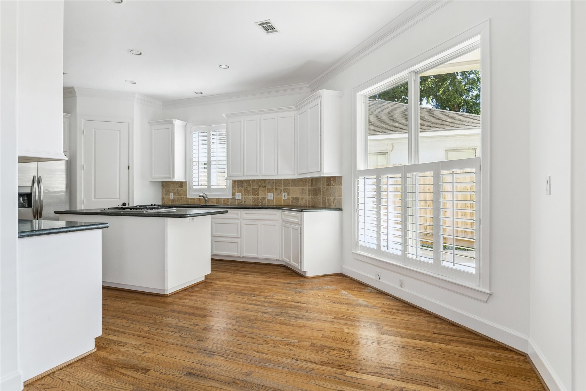 6106 Fordham Street Houston, TX 77005 - Photo 9 of 33 Open kitchen and breakfast area with granite countertops, tile backsplash, stainless appliances, and wraparound windows with plantation shutters.