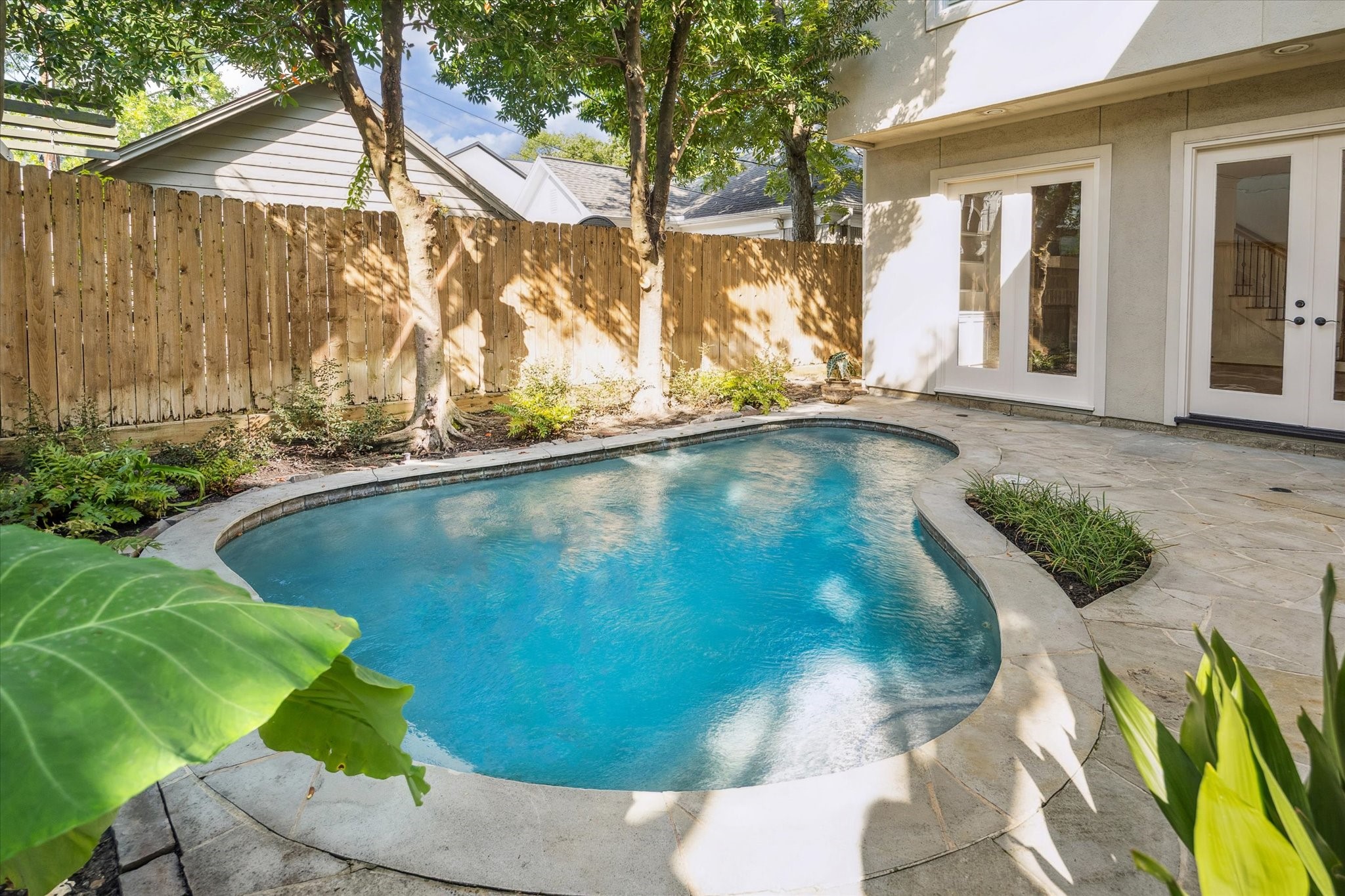 6106 Fordham Street Houston, TX 77005 - Photo 10 of 33 Private backyard oasis with a flagstone patio and sparkling pool bordered by lush greenery—perfect for relaxing or entertaining outdoors.