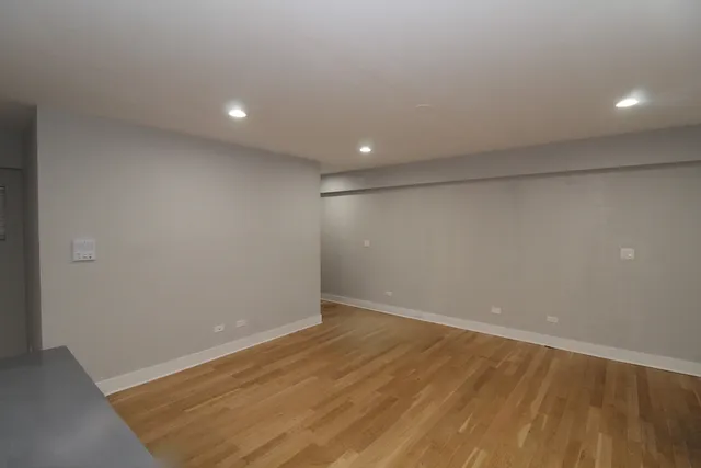 an empty room with wooden floor and natural light