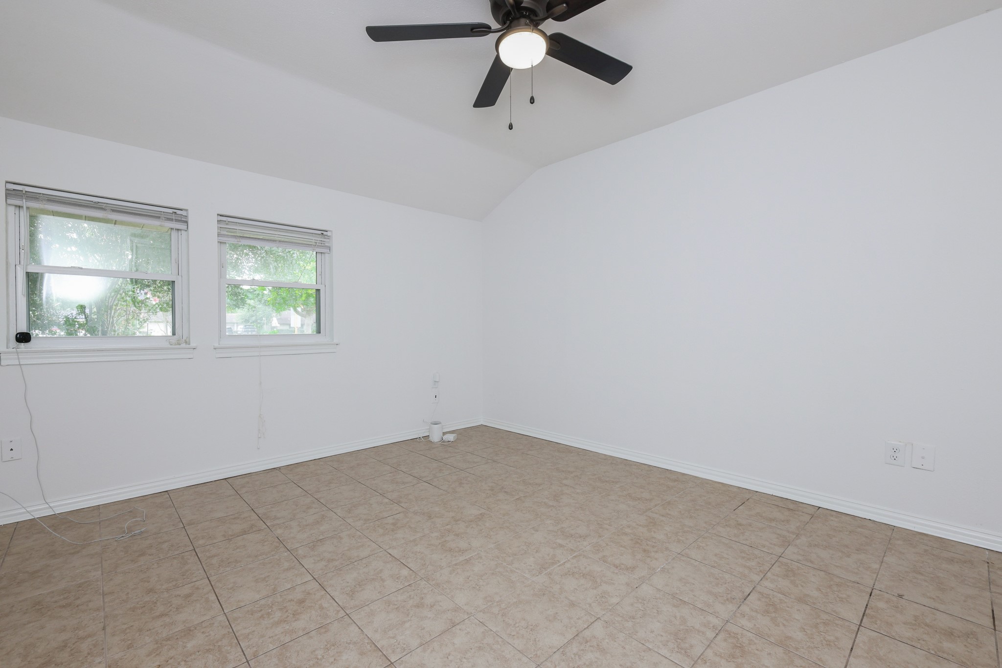 4823 Connorvale Road Houston, TX 77039 - Photo 13 of 26 Primary bedroom features white walls and tiled flooring. It has two windows allowing natural light and a ceiling fan for comfort.