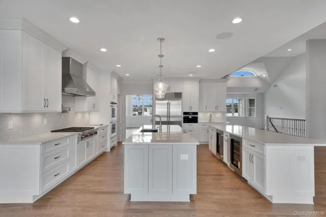 a large kitchen with stainless steel appliances kitchen island granite countertop a large counter top a sink dishwasher a stove and a refrigerator