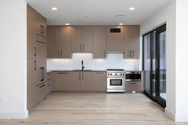 a large white kitchen with a large window and stainless steel appliances