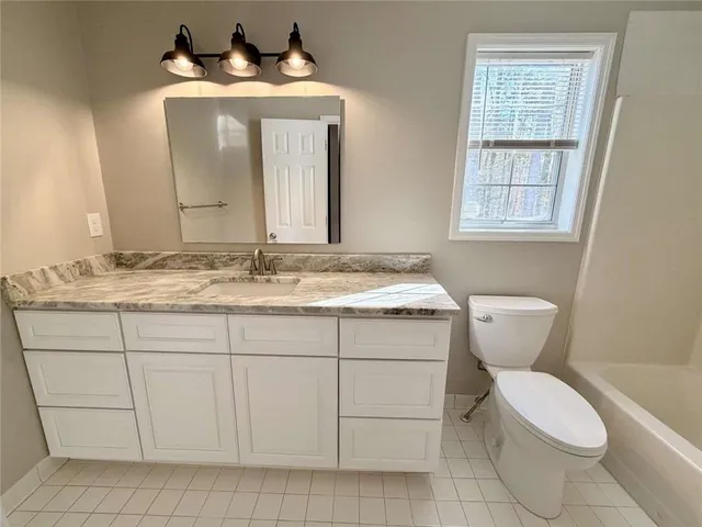 a bathroom with a granite countertop toilet sink and mirror