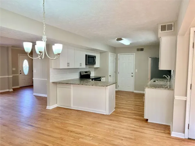 a kitchen with a refrigerator a stove cabinets and wooden floor