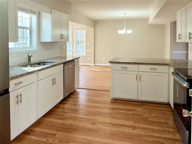 a kitchen with stainless steel appliances granite countertop a stove a sink and white cabinets