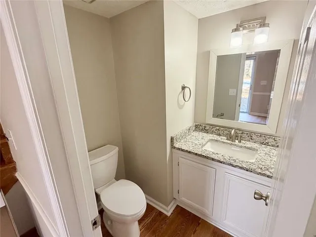 a bathroom with a granite countertop toilet sink and mirror