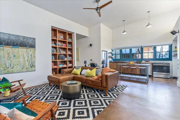 a living room with furniture a bookshelf and a large window