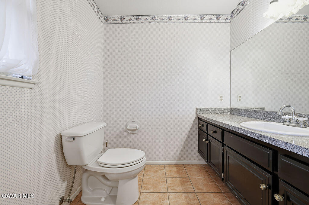 711 Lisa Street Palmdale, CA 93551 - Photo 23 of 66 a bathroom with a granite countertop toilet sink and mirror