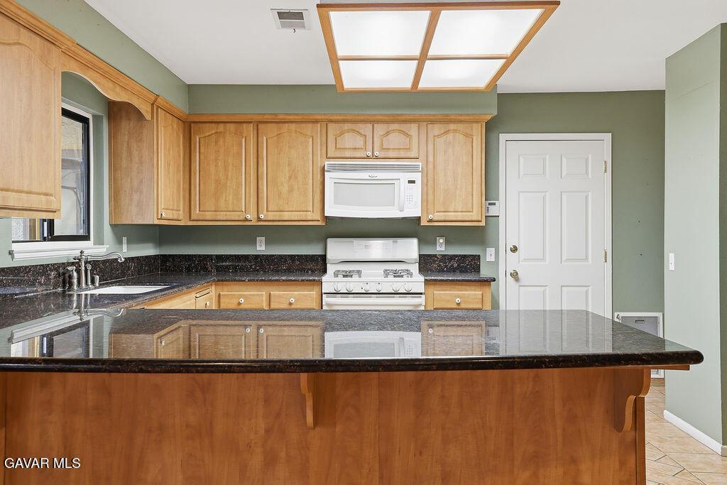 711 Lisa Street Palmdale, CA 93551 - Photo 33 of 66 a kitchen with stainless steel appliances granite countertop a sink and a granite counter tops