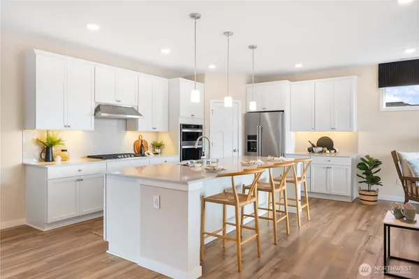 a kitchen with a table chairs wooden floors and a view of living room