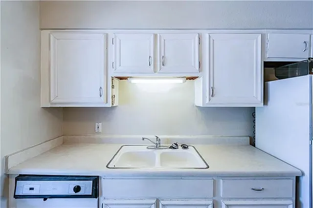 a kitchen with white cabinets and sink
