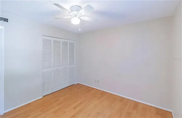 an empty room with a chandelier fan and windows