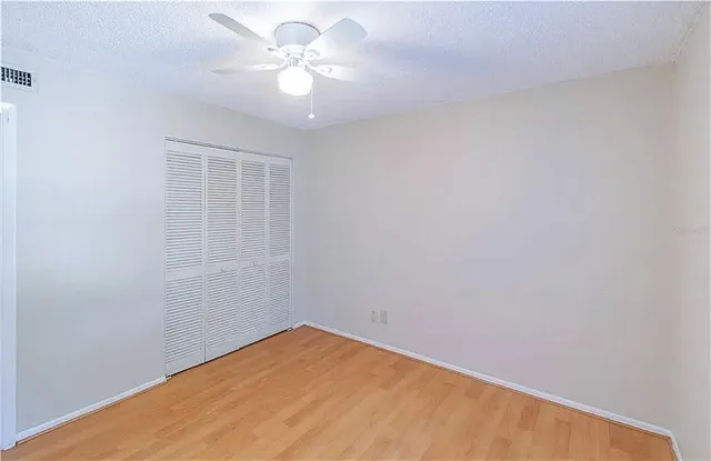 an empty room with a chandelier fan and windows