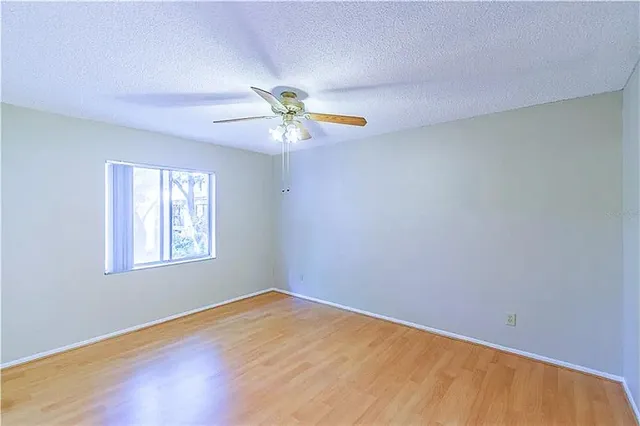 an empty room with a window and a fan