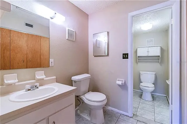 a bathroom with a toilet sink vanity granite and mirror