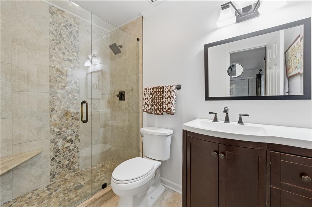 1102 Moorestown Circle Decatur, GA 30033 - Photo 11 of 13 a bathroom with a toilet a sink a glass door a shower a mirror a vanity and a shower