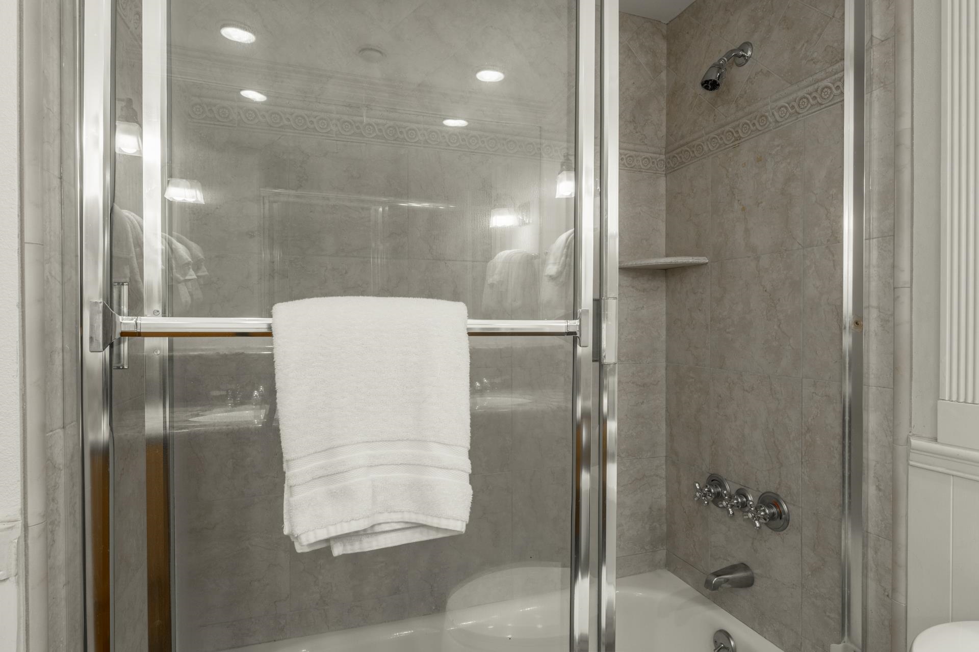 165 Old Mammoth Road, Unit 3 Mammoth Lakes, CA 93546 - Photo 23 of 48 Tub and shower combination featuring a glass enclosure with chrome framing, tiled walls with decorative band, built-in shelving, and recessed lighting