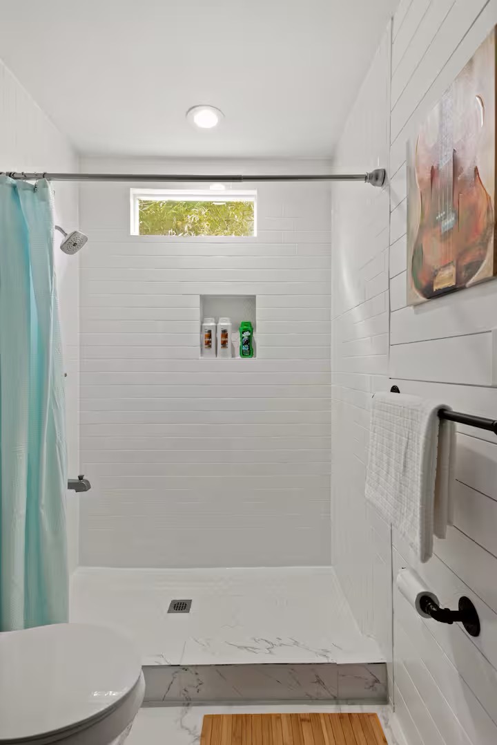 307 East 35th Street, Unit A Austin, TX 78705 - Photo 36 of 40 A well-lit, contemporary shower with a convenient built-in niche and sleek white shiplap-style walls.