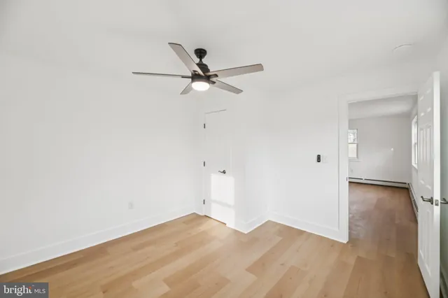 an empty room with wooden floor and ceiling fan