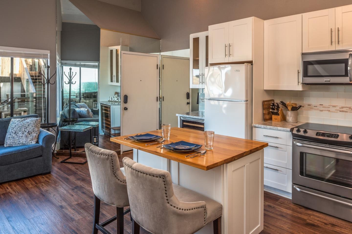 1 Surf Way, Unit 225 Monterey, CA 93940 - Photo 12 of 32 a kitchen with stainless steel appliances granite countertop a refrigerator a stove a sink a dining table and chairs