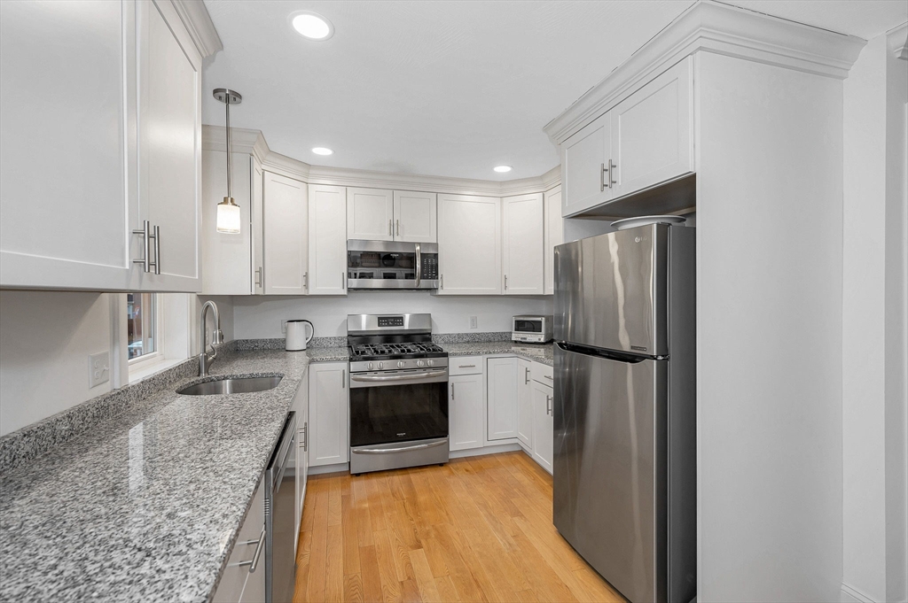 154 Chestnut Street, Unit 9 Lowell, MA 01852 - Photo 11 of 39 a kitchen with kitchen island granite countertop a refrigerator a stove top oven a sink and dishwasher