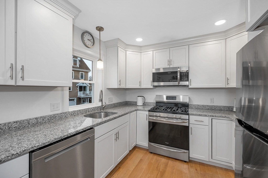 154 Chestnut Street, Unit 9 Lowell, MA 01852 - Photo 12 of 39 a kitchen with granite countertop white cabinets and white appliances