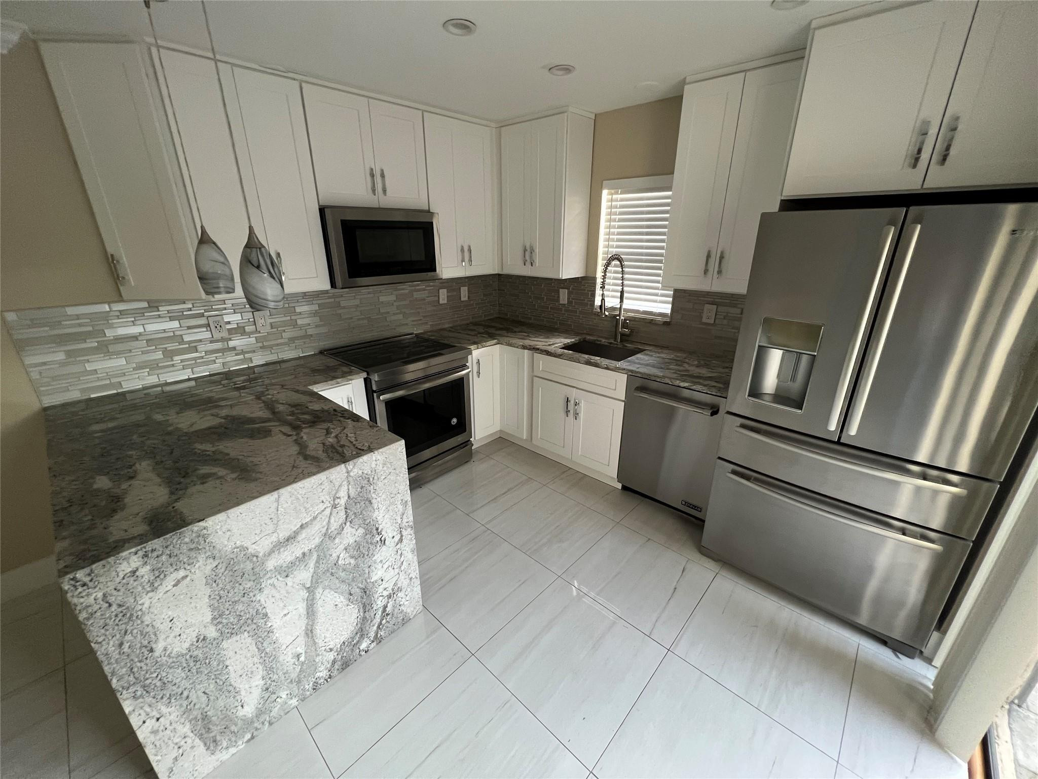 9380 Southwest 61st Way, Unit C Boca Raton, FL 33428 - Photo 1 of 32 a kitchen with granite countertop a refrigerator stove and microwave
