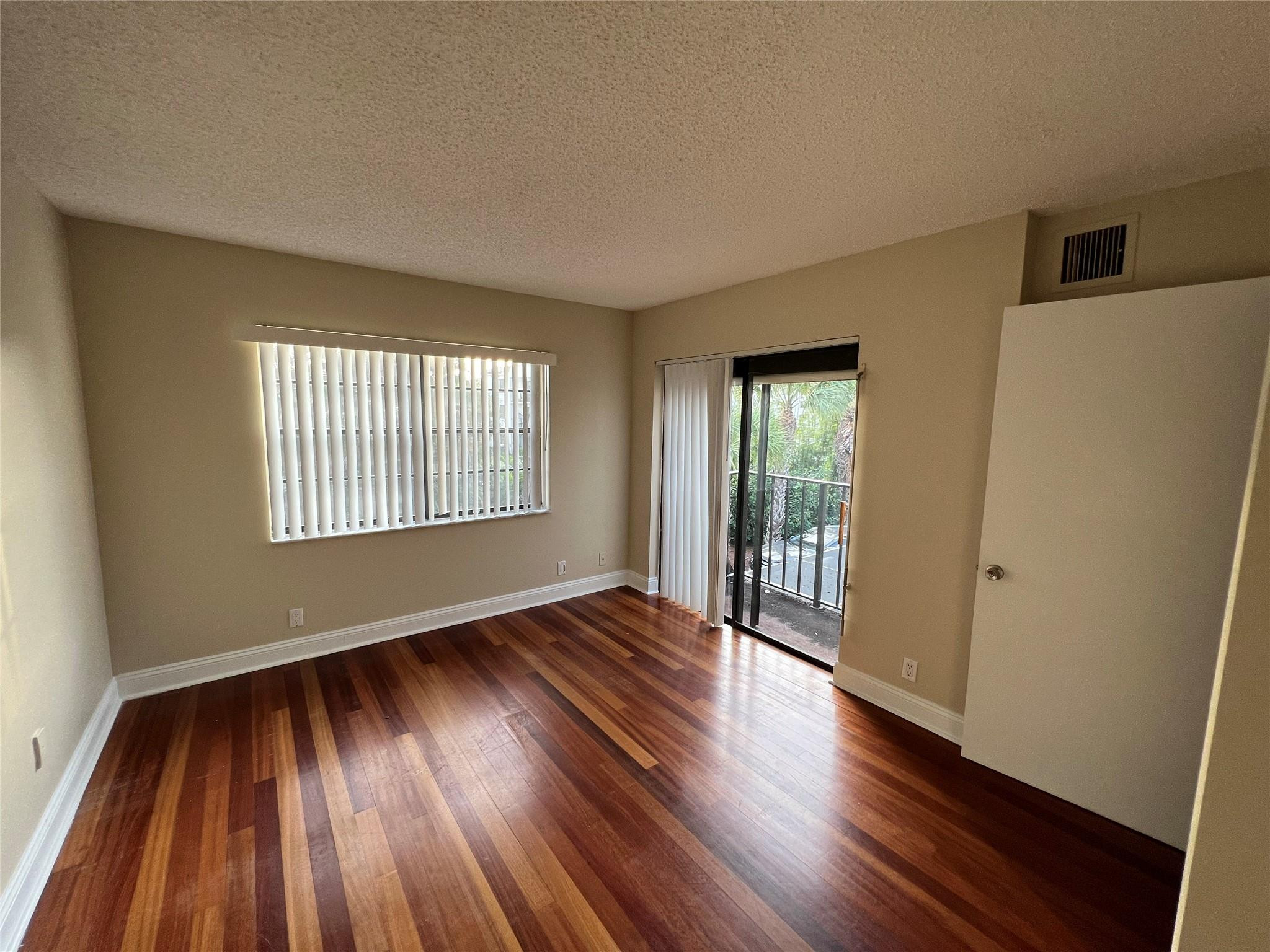 9380 Southwest 61st Way, Unit C Boca Raton, FL 33428 - Photo 10 of 32 a view of an empty room with wooden floor and a window