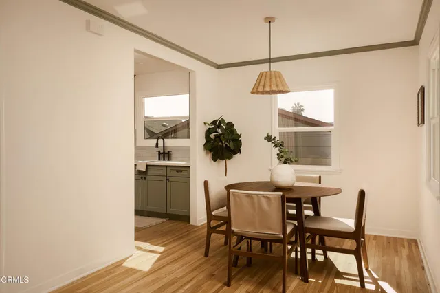 a kitchen with stainless steel appliances a stove a microwave a dining table and chairs with wooden floor