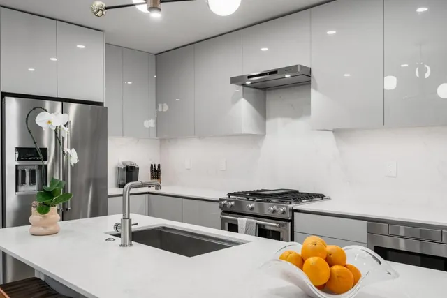 a kitchen with stainless steel appliances granite countertop a sink a stove and a refrigerator