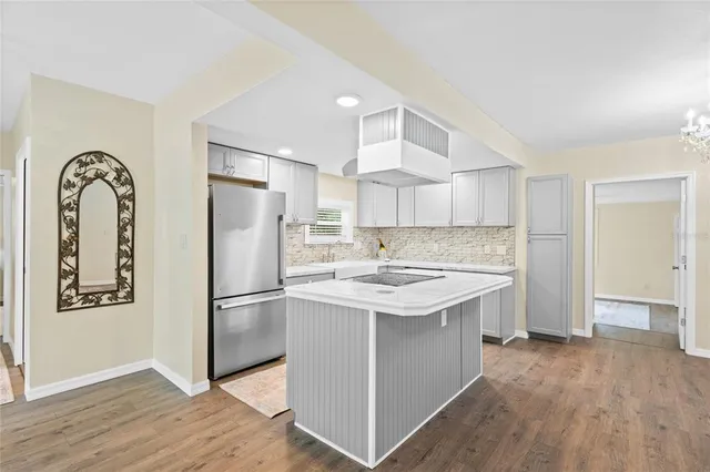 a kitchen with stainless steel appliances kitchen island granite countertop a refrigerator and a sink