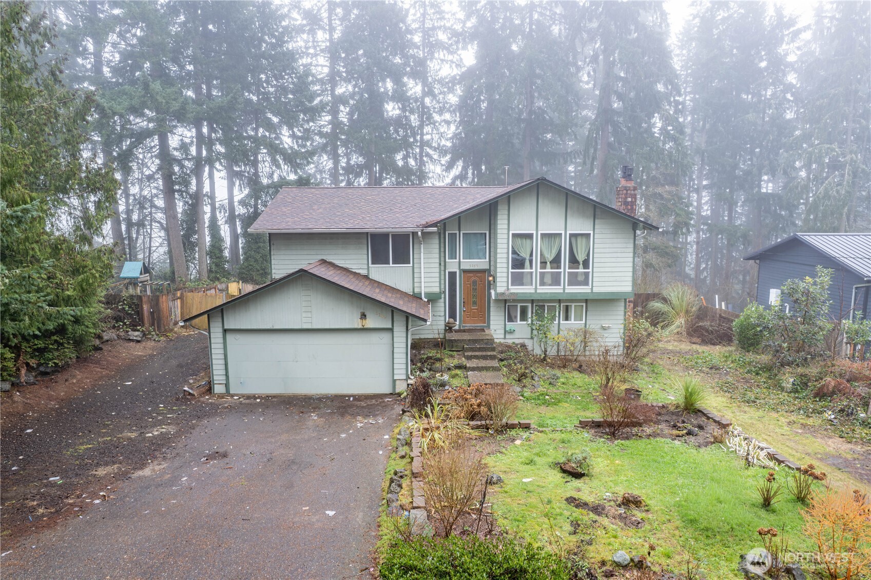 a front view of a house with a yard and large tree