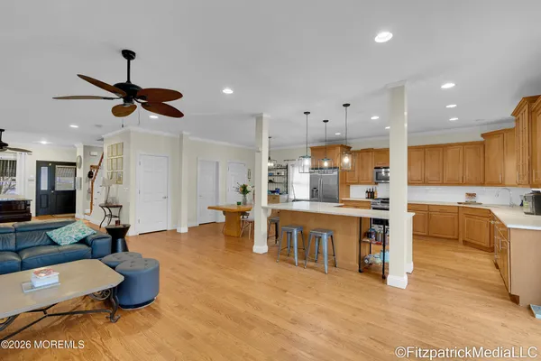 a large kitchen with kitchen island a white counter space a sink appliances and a living room view